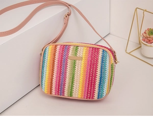 Detail of colorful striped straw crossbody bag with pink strap and golden hardware