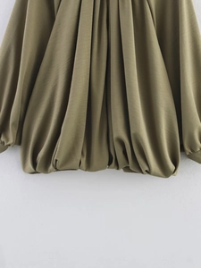 Close-up of olive green pleated hem detail on a long sleeve puff jacket with fine fabric drape
