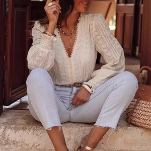 Close-up of white V-neck lace blouse with intricate embroidery and lantern sleeves
