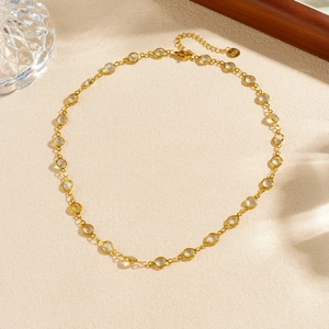 Minimalist gold plated stainless steel necklace with clear crystals on beige background