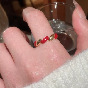 Detailed view of a red enamel and gold plated twisted ring on a woman finger