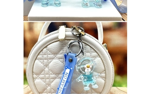 Macro detail of blue astronaut quicksand bottle keychain with silicone Dream On wrist strap