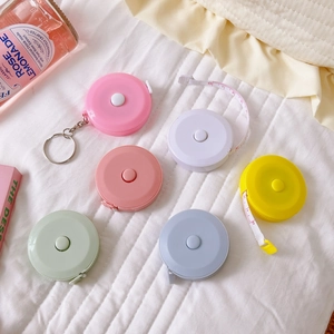 Flat lay of colorful 1.5m mini retractable tape measures on white quilted fabric