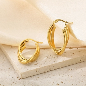 Minimalist triple-layer irregular gold oval hoop earrings on textured sandstone and silk