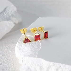 Detail of S925 silver stud earrings set with red geometric stones and gold plating