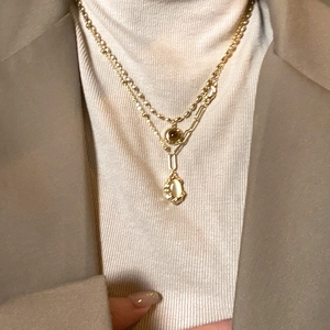 Close-up of double-layered gold bamboo oval necklace with brown and light gems
