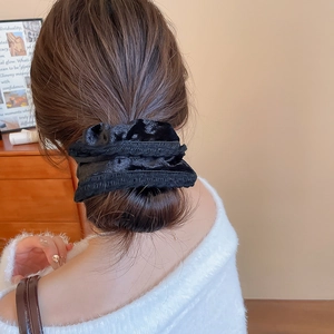 Close-up of a black velvet scrunchie worn on a ponytail for an elegant look