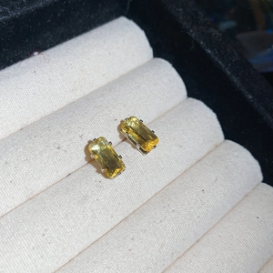 Close-up of yellow emerald-cut gemstone stud earrings in a beige velvet jewelry box