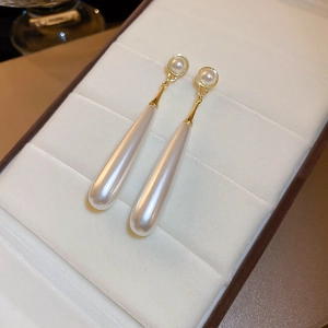 Detail of elegant teardrop pearl earrings with gold accents in a beige jewelry box