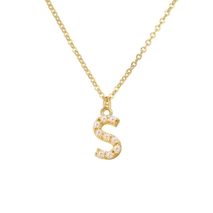 Detailed close-up of a gold necklace with a pearl-studded S-shaped letter pendant