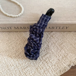 Détail de la texture en tissu quadrillé bleu et du fermoir sécurisé de la pince à cheveux