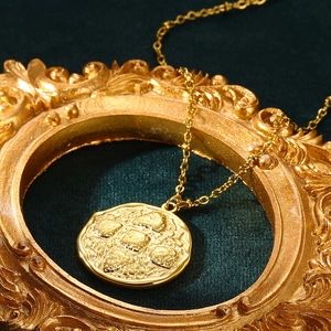 Macro detail of gold vintage coin pendant with textured surface on green velvet