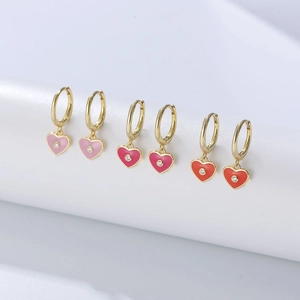 Three pairs of heart-shaped enamel drop earrings in pink and red with gold hoops