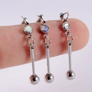 Detail of industrial barbell earrings with white opal and cubic zirconia on hand