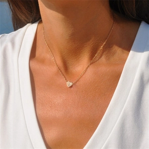 Gros plan d'un collier pendentif cœur doré minimaliste avec gravure de l'initiale J
