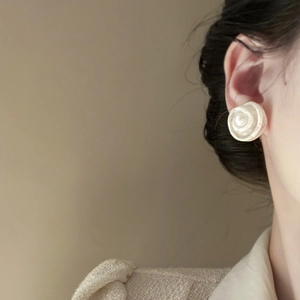 Detail shot of model wearing cream pearl flower stud earrings with delicate floral texture