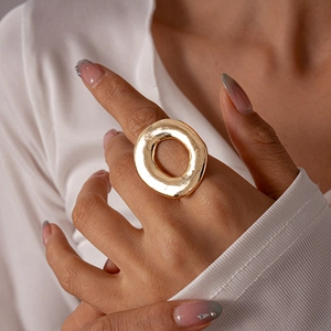 Detail of chunky gold hollow ring worn by model showing glossy metallic texture and bold design
