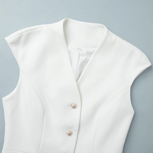 Detail of white V-neck vest with textured fabric and elegant pearl buttons with gold rims
