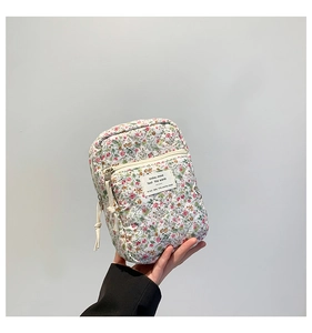Close-up of floral quilted cosmetic bag with front zipper pocket and tassel detail