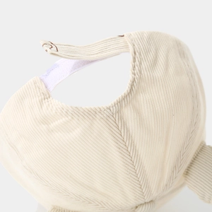 Detailed macro view of the cream corduroy baseball cap texture and back adjustment strap