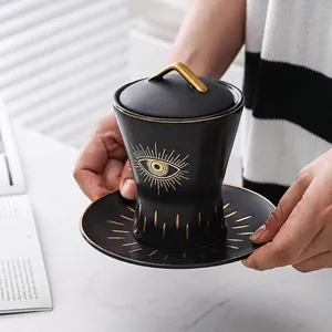 Matte black ceramic evil eye mug set with gold lid handle and matching saucer