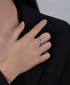 Detailed close-up of emerald-cut pink gemstone ring with pavé diamond accents on hand