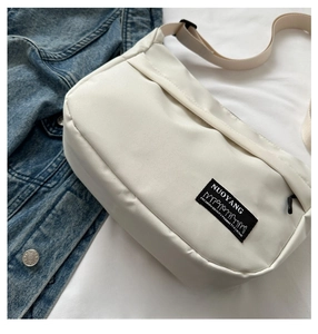 Detail of the white nylon crossbody bag featuring the signature black NUOYANG logo label