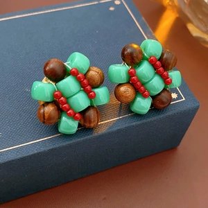 Close-up of handmade floral earrings with turquoise, brown wood, and red beads
