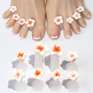 Detailed view of silicone toe separators with white and orange floral nail art decor