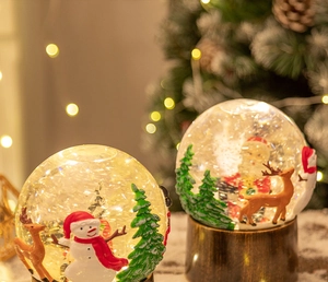 Gros plan d'une boule à neige de Noël lumineuse avec Père Noël et renne et lumières chaudes