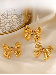 Dettaglio macro di set di gioielli a fiocco placcati oro 18K con strass lucidi sulla seta