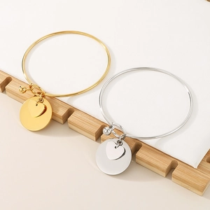 Detailed shot of gold and silver minimalist heart charm bangles on wooden display tray