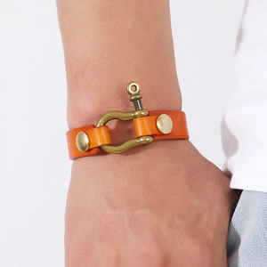 Close-up of an orange top-grain leather bracelet with brass horseshoe shackle and rivets