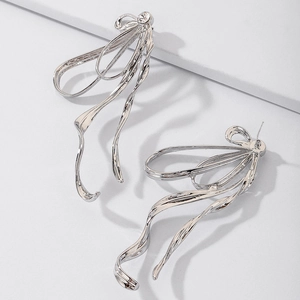 Detailed view of silver bow earrings with long tassels on a modern minimalist pedestal
