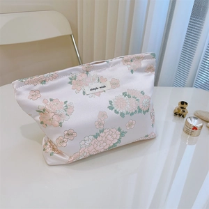 Detailaufnahme der rosa Satin-Kosmetiktasche mit Blumenmuster und einfachem Wunsch-Label