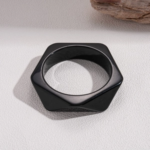 Polished black resin hexagonal geometric bangle on a textured minimalist background