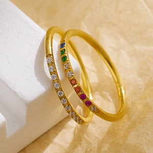 Detail of thin gold stackable rings with colorful rainbow and clear zircon stones