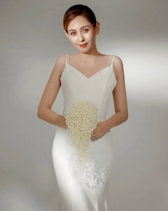 Detailed view of elegant bridal bouquet made of white pearls with white sling formal dress
