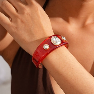Detail of a red resin cuff bracelet with large crystal stones and micro-pave accents