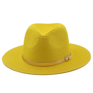Close-up of yellow straw fedora hat featuring a gold faux leather band and metal buckle