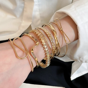 Close-up of minimalist gold layered bracelets with geometric and hammered metal textures