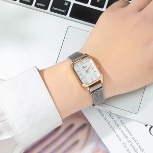 Detail of rose gold octagonal quartz watch with silver mesh strap on wrist