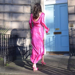 Detail of the bright pink satin long dress featuring a backless drape design on a model