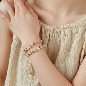 Detailed view of double heart zircon bracelets in gold with pink and white center stones