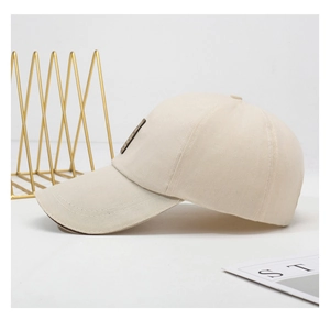 Detail view of a beige cotton baseball cap with a dark square patch on a white background
