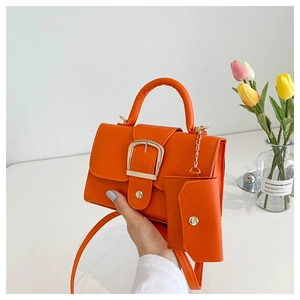 Detail of orange crossbody bag featuring lychee texture and small coin purse attachment