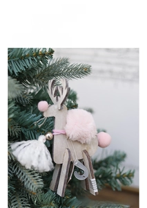 Close-up of wooden reindeer ornament with pink felt ball, golden bell and white tassel