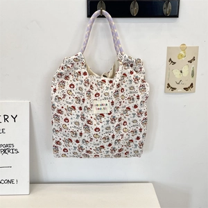 Detail of quilted cartoon tote bag with purple woven ropes hanging on a minimal white wall