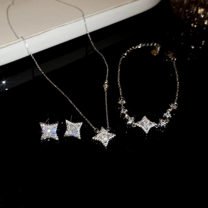 Detailed view of sparkling star necklace, bracelet and earrings jewelry set on dark surface