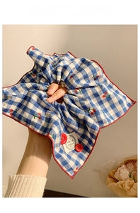 Close-up of blue plaid scrunchie with cherry embroidery and hand made fabric label
